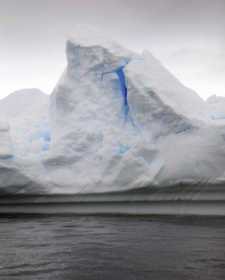 A+bright+brilliant+blue+glows+from+within+an+Antarctic+iceberg