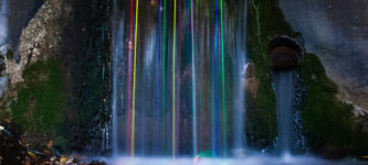 Long+exposure+shot+of+glow+sticks+dropped+into+a+waterfall.