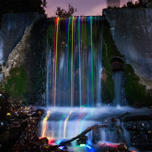 Long+exposure+shot+of+glow+sticks+dropped+into+a+waterfall.