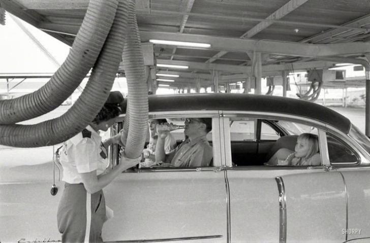 Getting+cooled+air+piped+into+the+car+while+enjoying+a+meal+at+a+drive-in+restaurant.+Houston%2C+Texas%2C+1957.