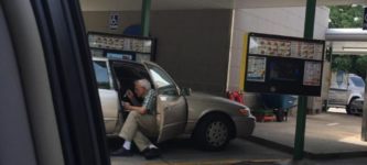 An+elderly+man+sitting+outside+of+his+car+door+spoon+feeding+his+wife+ice+cream