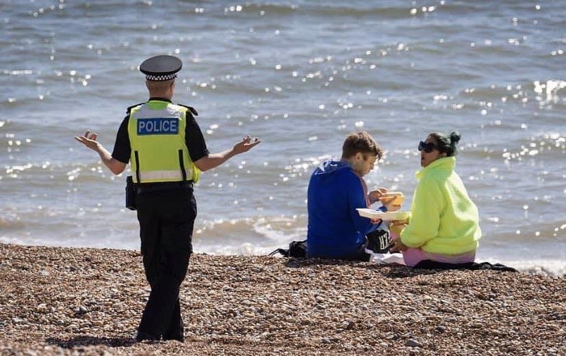 Police+Officer+confronting+two+people+having+lunch+on+a+Beach+during+Quarantine.