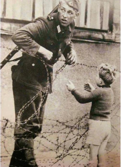 An+East+German+soldier+helps+a+young+boy+cross+the+newly-erected+Berlin+Wall+in+1961